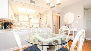 Una cucina moderna con un tavolo da pranzo in vetro, sedie bianche e un lampadario.
