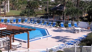 Zona de piscina con sillas reclinables azules y vista al océano.
