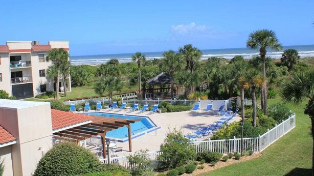 A resort with a pool, beach chairs, and palm trees. - Ocean Village Club Condo D17 (St. Augustine)
