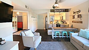 A compact living space with a kitchenette, a dining area with stools, a sofa, and a TV. - Ocean Village Club Condo D17 (St. Augustine)