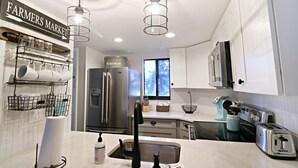 A modern kitchen with white cabinets, stainless steel appliances, and a 'Farmers Market' sign. - Ocean Village Club Condo D17 (St. Augustine)