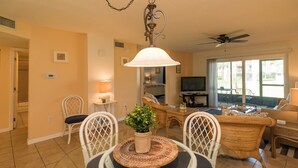 A spacious living room with a dining area, a TV, and a ceiling fan.
