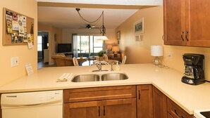 A kitchen with wooden cabinets, a double sink, and a coffee maker.