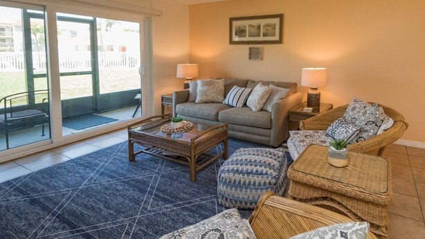 A living room with a sofa, two side tables with lamps, a coffee table, and wicker furniture.