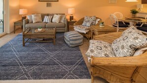 A cozy living room with a sofa, two armchairs, a coffee table, and a dining table with chairs.