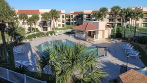 Un hotel con piscina, sillas de descanso y palmeras.
