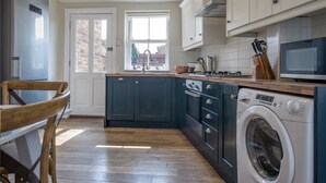 A kitchen with dark blue cabinets, a washing machine, and a microwave.