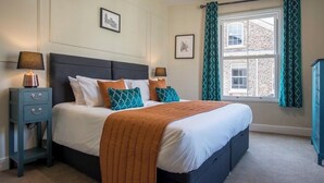 A neatly arranged bedroom with a bed, two bedside tables, and a window with curtains.