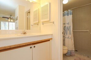 A bathroom with a white vanity, a mirror, a ceiling fan, and a shower curtain with a striped pattern. - Ocean Village Club Condo H21 (St. Augustine)
