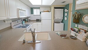 A compact kitchen with white appliances, a skylight, and a view of the living area. - Ocean Village Club H31 (St. Augustine)