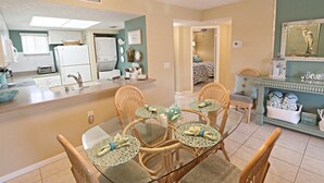 A compact kitchen with a dining area, a small living space, and a bedroom visible through an open door. - Ocean Village Club H31 (St. Augustine)