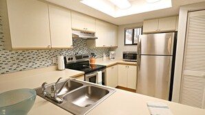 A compact kitchen with a double sink, a stove, a microwave, and a refrigerator. - Ocean Village Club Condo J16 (St. Augustine)
