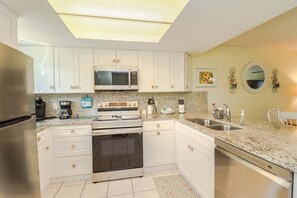 A kitchen with white cabinets, stainless steel appliances, a microwave, stove, and a dishwasher.