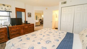 A bedroom with a bed, dresser, and a television on a desk. - Ocean Village Club Condo L26 (St. Augustine)