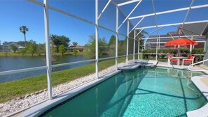 A pool with a clear blue water, surrounded by a white fence, and a red umbrella.