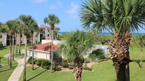 A resort with a pool area, palm trees, and a building with a red-tiled roof. - Ocean Village Club Condo O32 (St. Augustine)