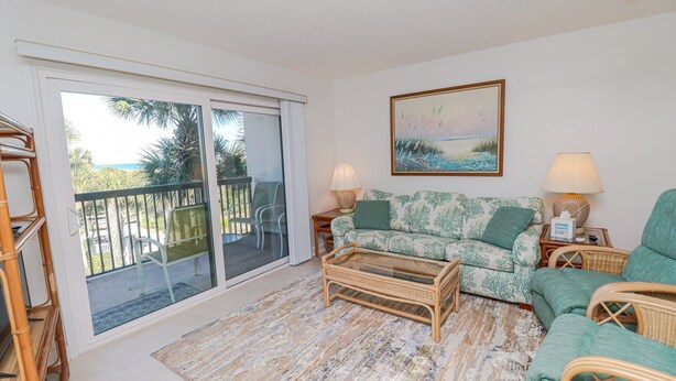 Un salon comprenant un canapé, deux tables d’appoint, une table basse et un tableau accroché au mur.