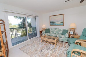 A living room with a sofa, two side tables, a coffee table, and a painting on the wall.