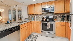 Une cuisine moderne avec des meubles en bois, des appareils électroménagers en acier inoxydable et un plan de travail en granit.