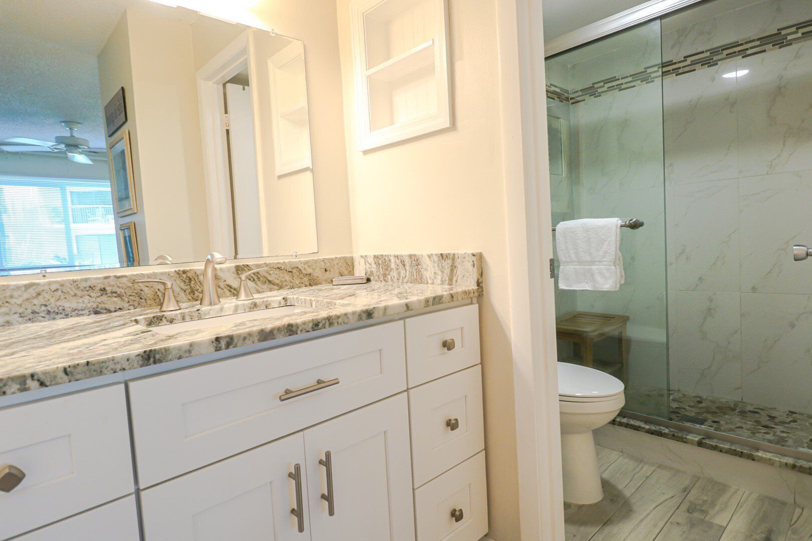 Un bagno con un top in marmo, un water e un box doccia in vetro.