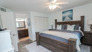 A bedroom with a wooden bed, a ceiling fan, a nightstand, and a dresser. - Ocean Village Club Condo P18 (St. Augustine)