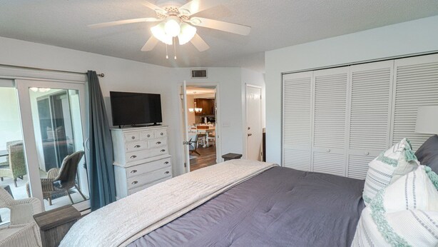 A bedroom with a bed, a television, a wardrobe, and a ceiling fan. - Ocean Village Club Condo P18 (St. Augustine)