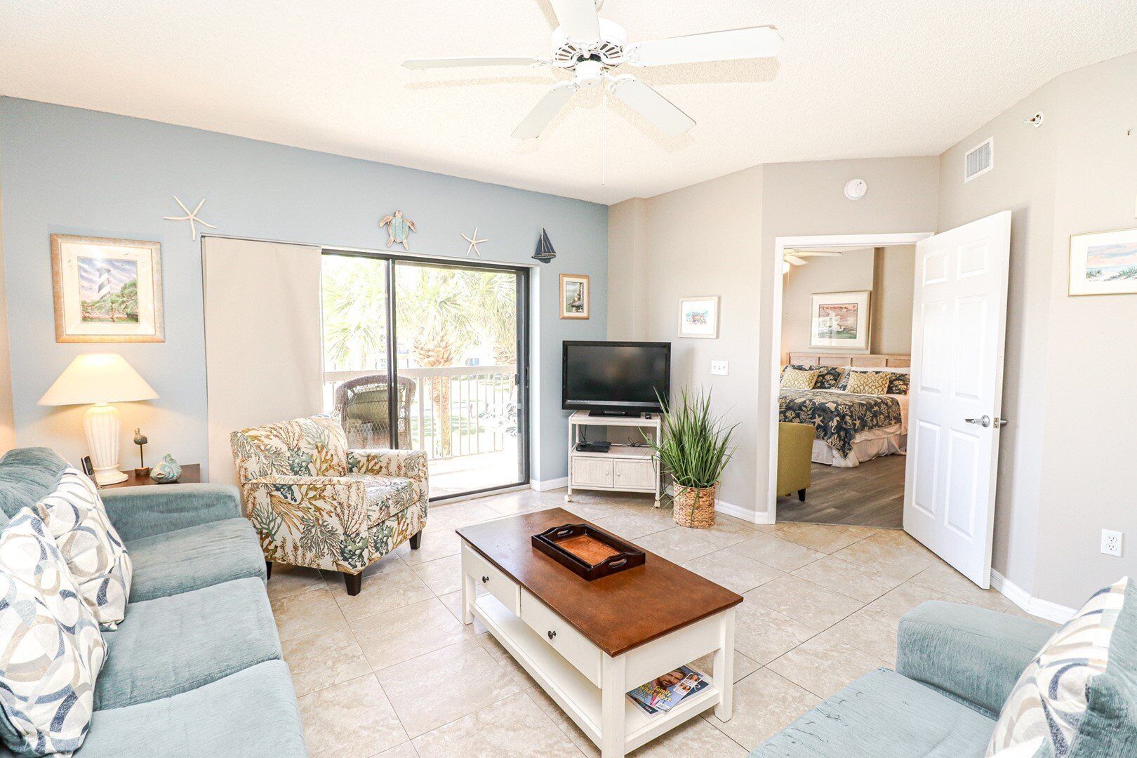 A living room with a TV, two sofas, a coffee table, and a ceiling fan.