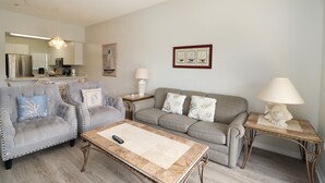Un salon avec un canapé, des fauteuils, une table basse et une lampe.