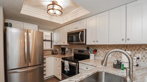 Una cocina moderna con electrodomésticos de acero inoxidable, armarios blancos y encimera de mármol.