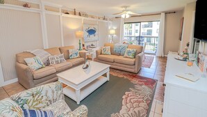 A living room with two beige sofas, a white coffee table, and a patterned rug.