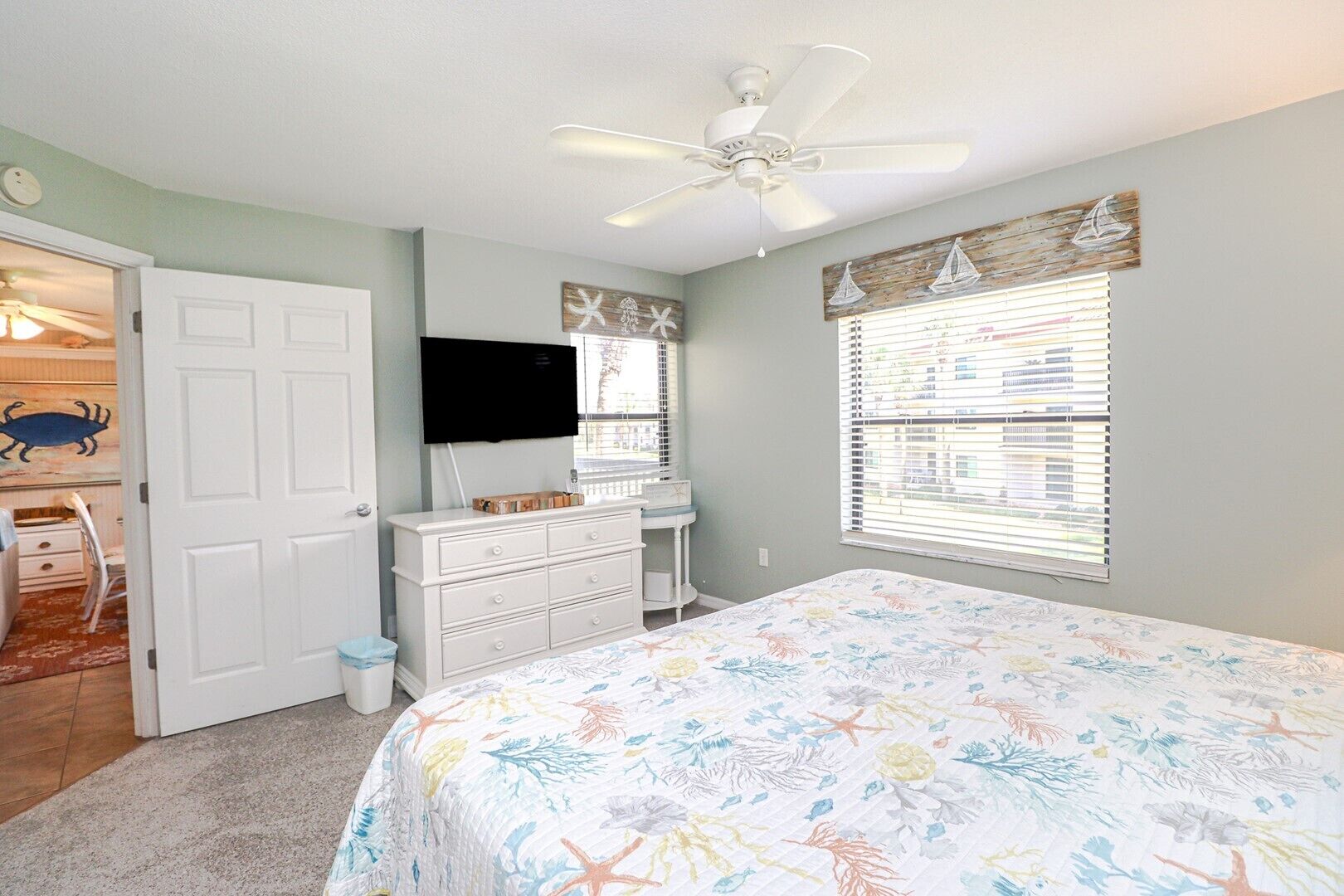 A bedroom with a bed, dresser, television, and a window with blinds.