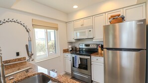 A modern kitchen with granite countertops, stainless steel appliances, and white cabinetry.