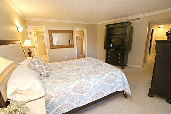 A bedroom with a bed, a dresser, a mirror, and a nightstand.