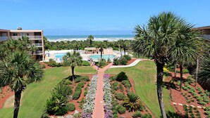 Ein Hotel mit Pool, Palmen und Meerblick.