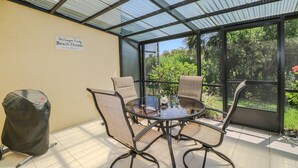 Un espace extérieur abrité, avec une table et des chaises, une poubelle et un panneau indiquant : « La maison de plage de la famille Zamperu, fondée en 2018 ».