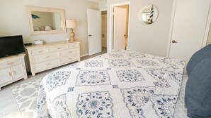 Un dormitorio con cama, cómoda, televisor y espejo.