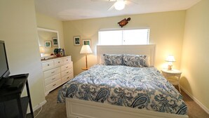A bedroom with a bed, dresser, lamp, and ceiling fan.
