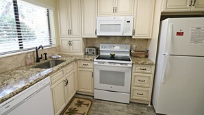 A kitchen with white cabinets, a microwave, a stove, a toaster, and a refrigerator.