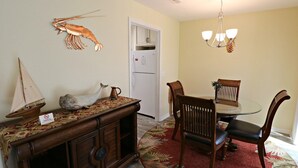 A dining area with a wooden table, chairs, a chandelier, and a decorative wall with a lobster and a sailboat.