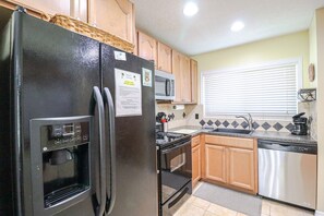 A compact kitchen with a black refrigerator, microwave, stove, and dishwasher.