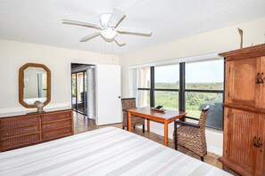 A bedroom with a bed, a dresser, a table with chairs, a ceiling fan, and large windows with a view. - Sea Place 11110-Three Bedroom Condo in Popular Sea Place Community (St. Augustine)