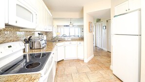 Una cocina con armarios blancos, estufa, fregadero y refrigerador.