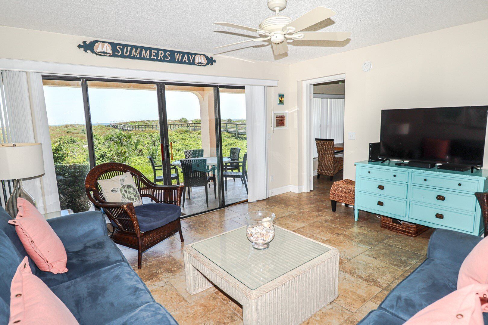 A living room with a TV, sofas, a coffee table, and a view of the outdoors.