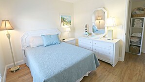 A bedroom with a bed, bedside tables, a dresser, a mirror, and a wardrobe. - Updated, Classy Ground Floor Condo-Sea Place 12119 (St. Augustine)