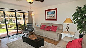 A living room with a sofa, armchair, and coffee table. There is a painting on the wall and a lamp on a side table. - Updated, Classy Ground Floor Condo-Sea Place 12119 (St. Augustine)