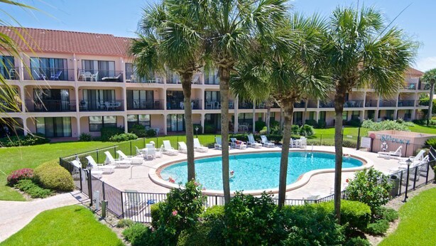 A hotel with a swimming pool surrounded by palm trees and lounge chairs. - Updated, Classy Ground Floor Condo-Sea Place 12119 (St. Augustine)