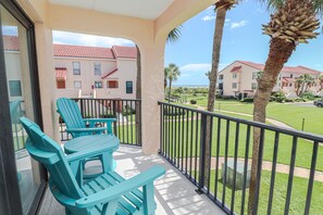 A balcony with turquoise chairs and a view of a residential area with palm trees and houses. - Luxury at the Beach, Totally Remodeled with Ocean Views Sea Place 12214! (St. Augustine)