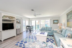 A spacious living room with a television, seating area, and a large window.