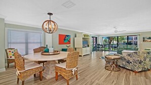 A spacious living room with a dining area, large windows, and a ceiling fan. - Luxury at the Beach, Totally Remodeled with Ocean Views Sea Place 12214! (St. Augustine)