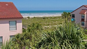 A beachfront property with a red-tiled roof, a view of the ocean, and a grassy area with palm trees. - Luxury at the Beach, Totally Remodeled with Ocean Views Sea Place 12214! (St. Augustine)